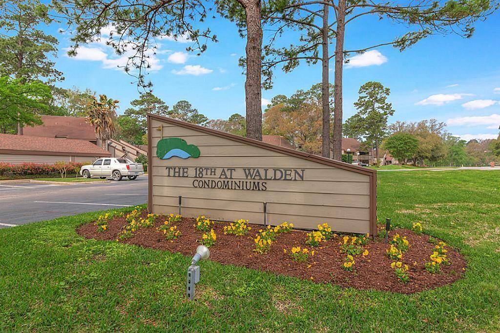 This photo shows the entrance to "The 18th at Walden Condominiums," featuring a landscaped sign surrounded by colorful flowers and trees.