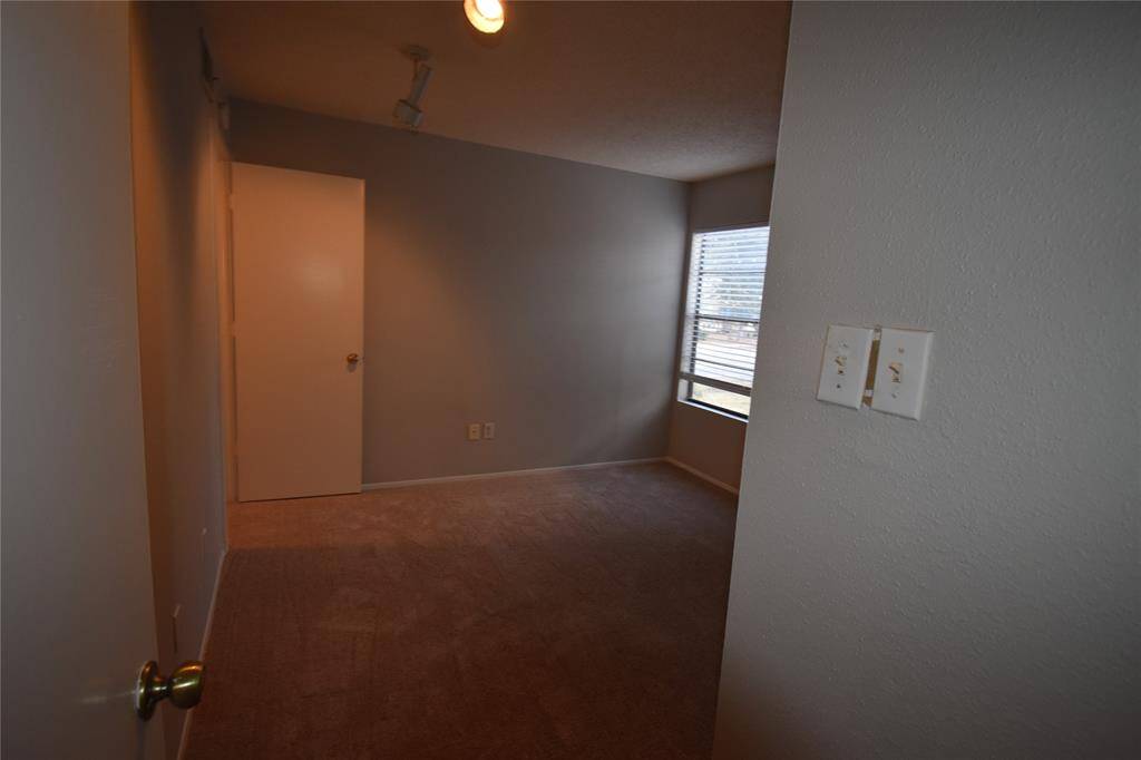 Primary bedroom carpeted with neutral walls, a window providing natural light.