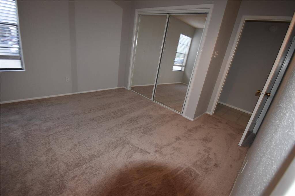 Primary bedroom with neutral walls, mirrored doors, allowing natural light.