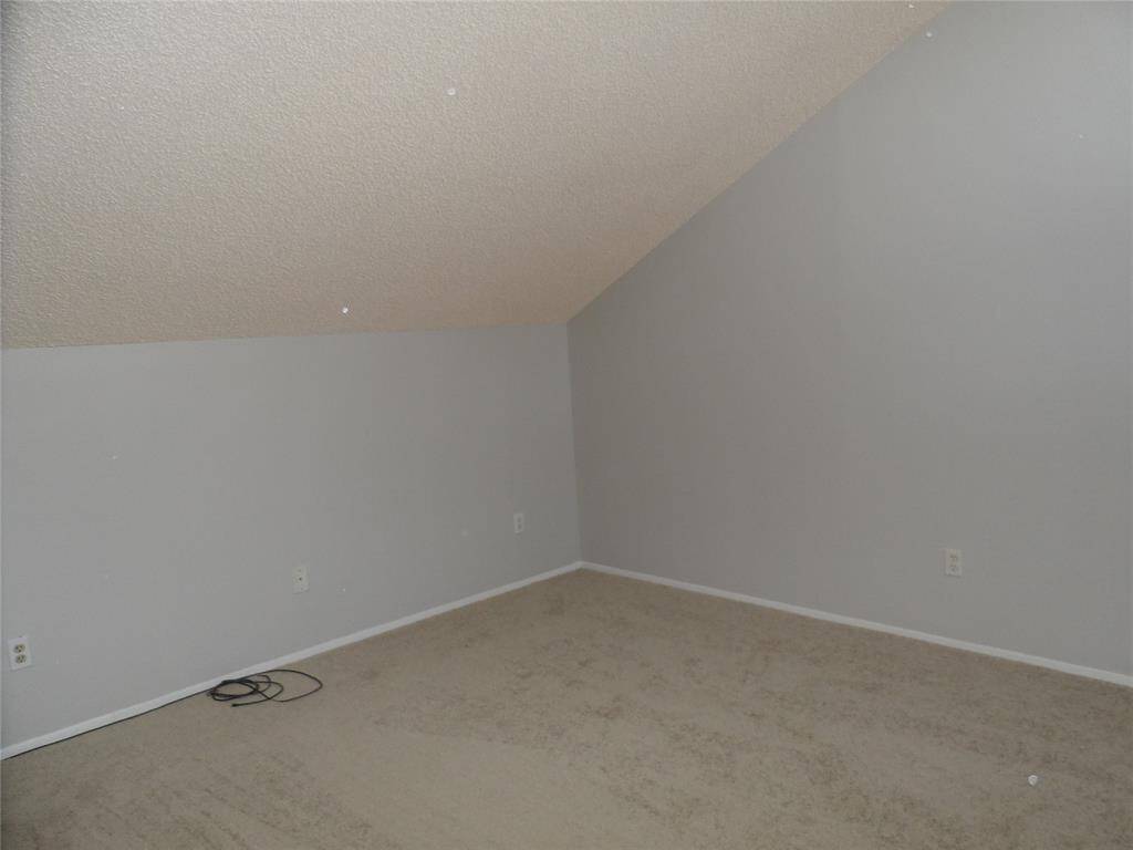This room features an angled ceiling, carpet, and walls, suitable for flexible room arrangements.