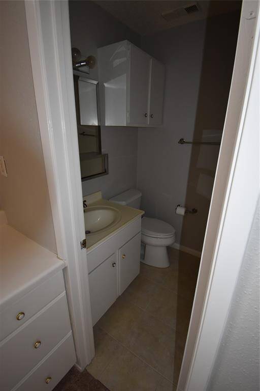 The 2nd bathroom with a sink vanity, toilet, and overhead storage cabinets. The space features neutral tones and tile flooring, offering a clean and functional design.