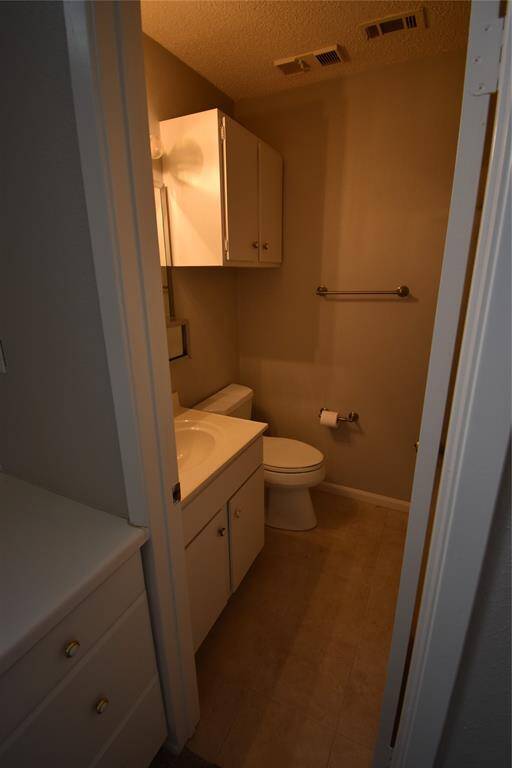 This photo shows a compact bathroom with a vanity, toilet, and overhead cabinet. Neutral tones and basic fixtures create a simple, functional space.