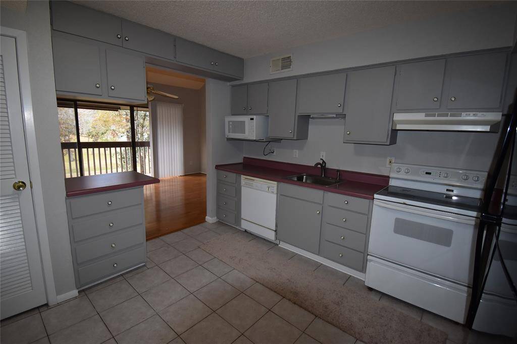 This photo shows a kitchen with gray cabinets and white appliances, including a stove, dishwasher, and microwave.