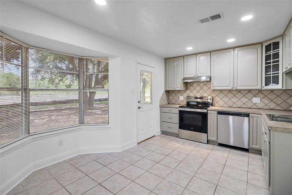 The bay window area is thoughtfully utilized to enhance the kitchen’s functionality, possibly featuring a built-in bench or small dining area that takes advantage of the extra light and views.