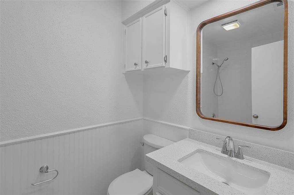 The clean, modern aesthetic features a sleek vanity with ample storage, a stylish countertop, and contemporary fixtures.