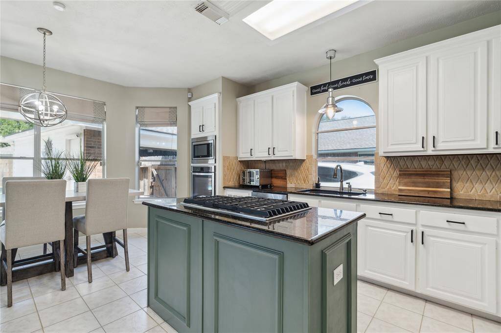 This angle shows the seamless flow from the kitchen to the breakfast area and into the rest of the home. The island doubles as a prep zone and casual dining space, while oversized windows keep everything bright and airy. It’s the perfect setup for morning coffee, after-school snacks, or weekend brunch.