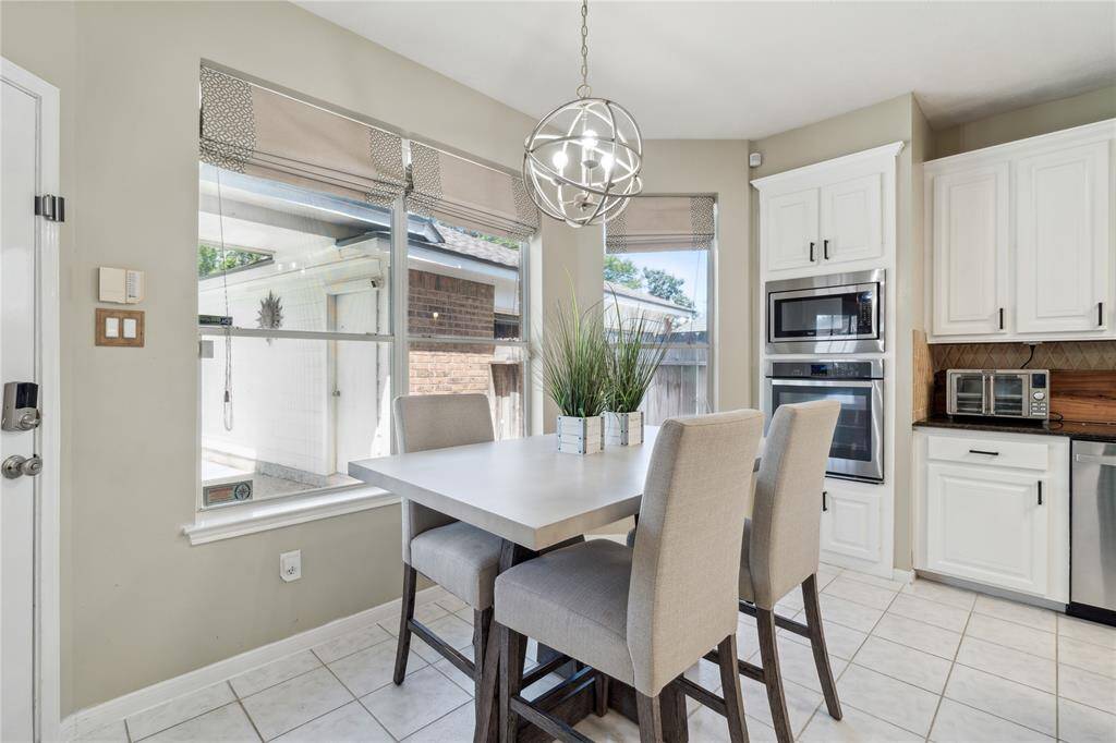 The breakfast nook offers a cozy corner with a modern globe chandelier and expansive windows overlooking the backyard.