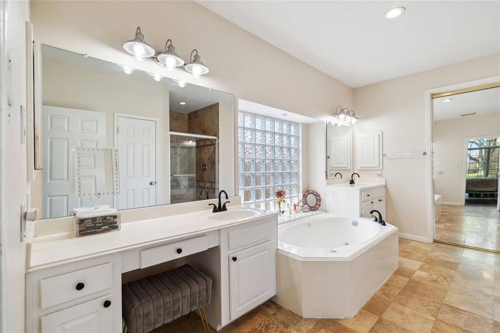 Step into a spa-like primary bath featuring a soaking tub, separate shower, and dual vanities with ample counter space and storage.