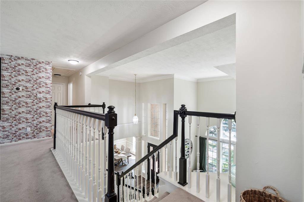 Overlooking the dramatic entryway, this upstairs landing adds architectural charm and a sense of openness. The clean white spindles and black handrail offer contrast and character, guiding you toward the upstairs bedrooms and flex spaces.