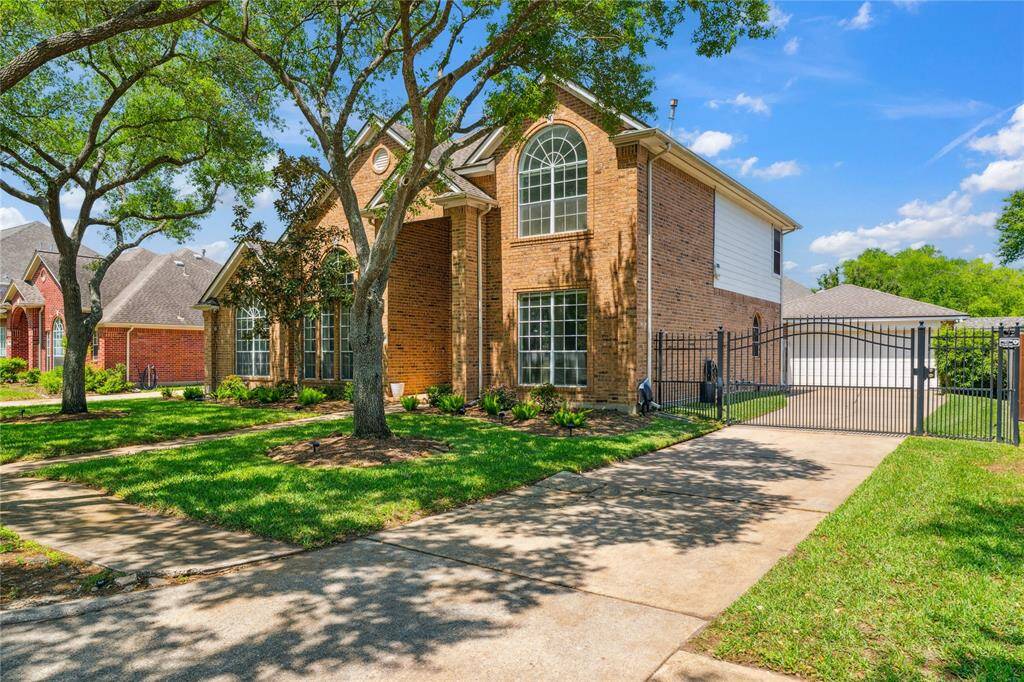 A side-angle view shows off the extended driveway leading to a gated entrance and detached garage—perfect for added security and privacy.