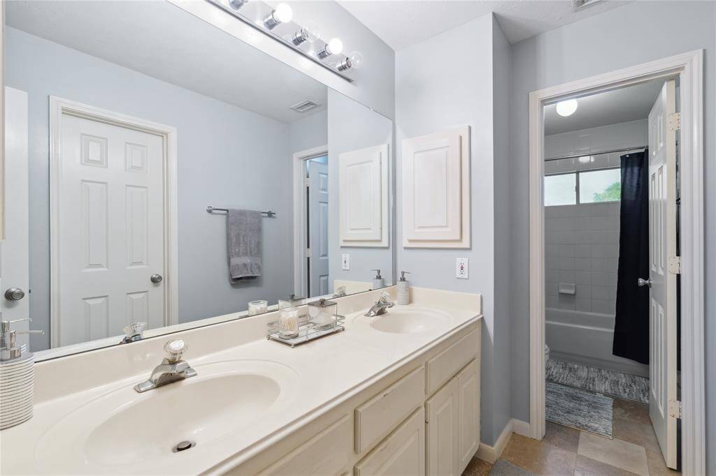 This full bathroom features double sinks, tons of counter space, and a privacy door leading to the tub/shower combo. It's the perfect setup for siblings or guests—stylish, functional, and easy to maintain.