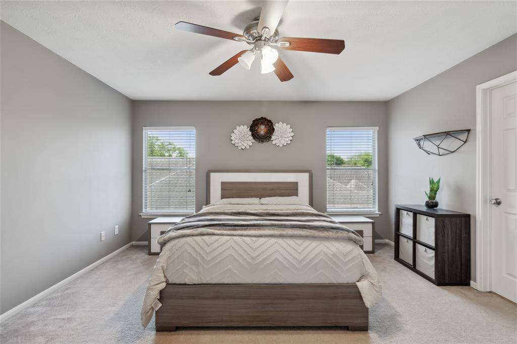 A serene and spacious bedroom with two large windows and room for a queen or king-sized bed. Clean lines and calm tones make this an inviting space to unwind after a long day.