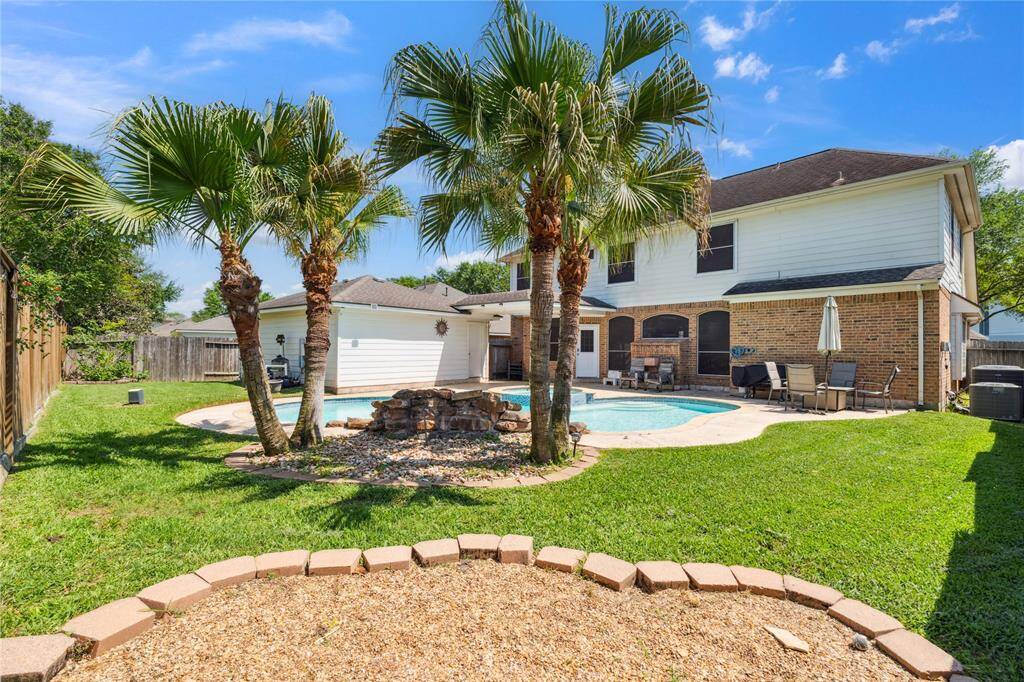 Palm trees, lush green grass, and a private fence line complete the backyard oasis. It’s the kind of outdoor space that feels like a vacation—every single day.