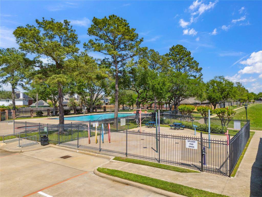 his photo captures the neighborhood’s gated splash pad and pool area, perfect for summertime fun and family-friendly recreation. The colorful water features and seating area offer a playful, shaded space for kids, while the surrounding greenery creates a peaceful park-like setting.