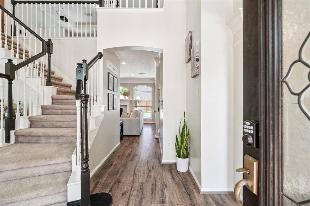 Step inside to a dramatic two-story foyer where natural light pours in from above. The curved staircase with black-and-white contrast gives a custom touch, and the rich wood flooring adds warmth and character. This entry sets the tone for a home that blends elegance with everyday livability.