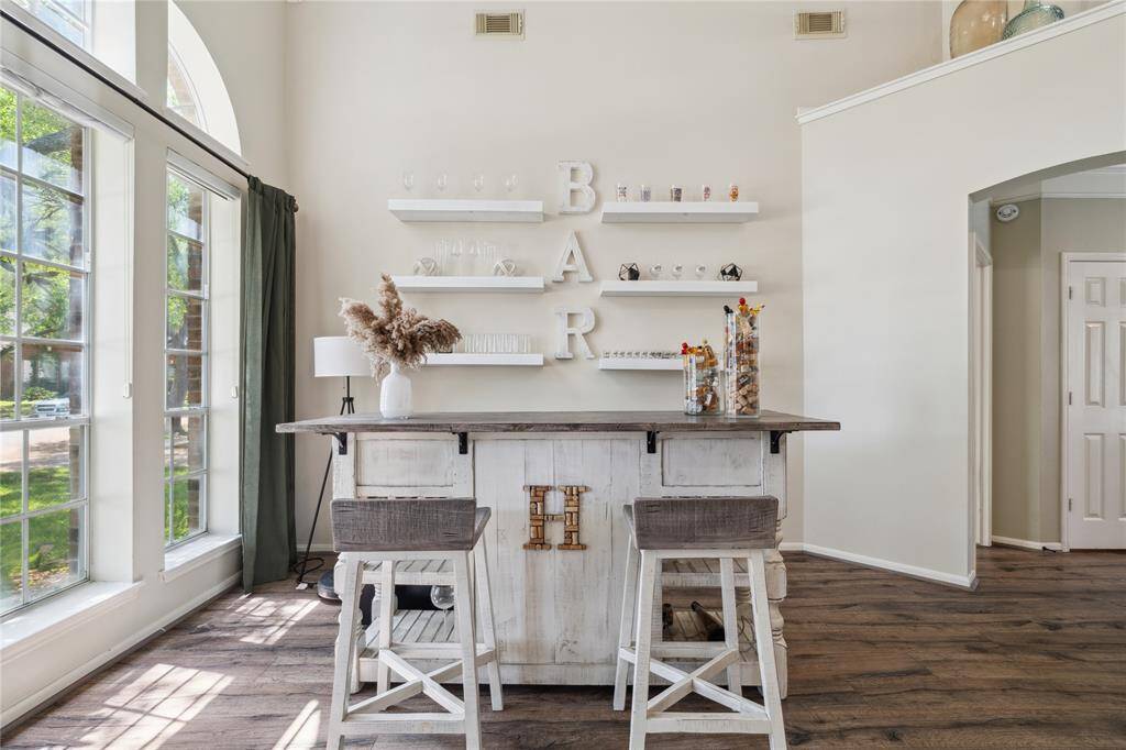 Entertain in style! This charming bar setup is nestled beneath soaring ceilings and statement windows. With rustic-modern shelving and a custom island, this space is ready for wine nights, cocktail hours, or a morning coffee bar—just steps from the main living areas.