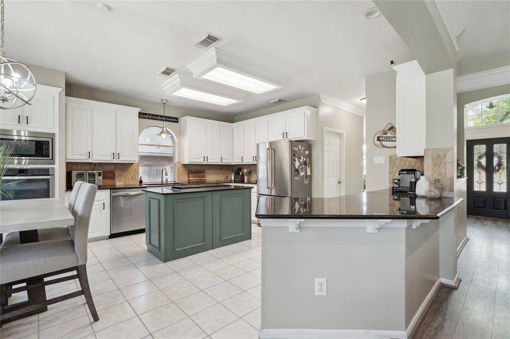 This kitchen checks all the boxes—bright, spacious, and beautifully updated. Crisp white cabinetry, granite countertops, and a bold green island with gas cooktop create a timeless yet modern feel. The open layout flows effortlessly into the breakfast nook, surrounded by windows that bring in soft natural light and views of the backyard. It’s a chef’s dream and an entertainer’s delight.