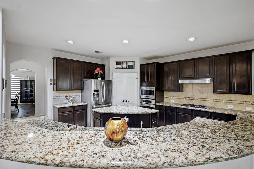 This gourmet kitchen includes a double oven, a modern range hood, and a large refrigerator.