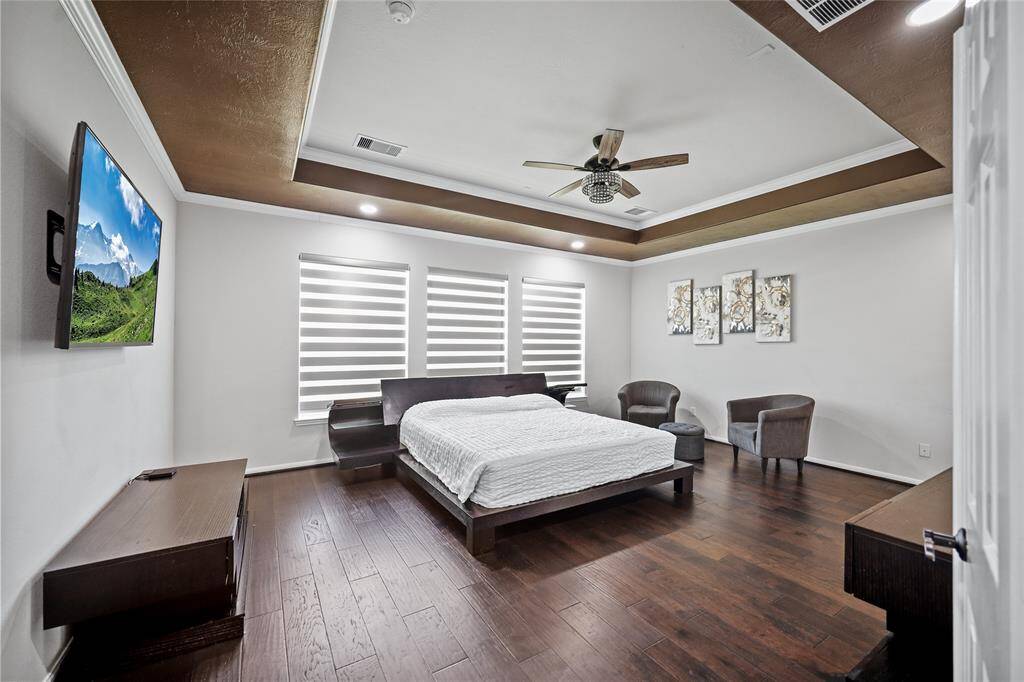 Expansive primary suite featuring an elegant tray ceiling and stunning hardwood floors.