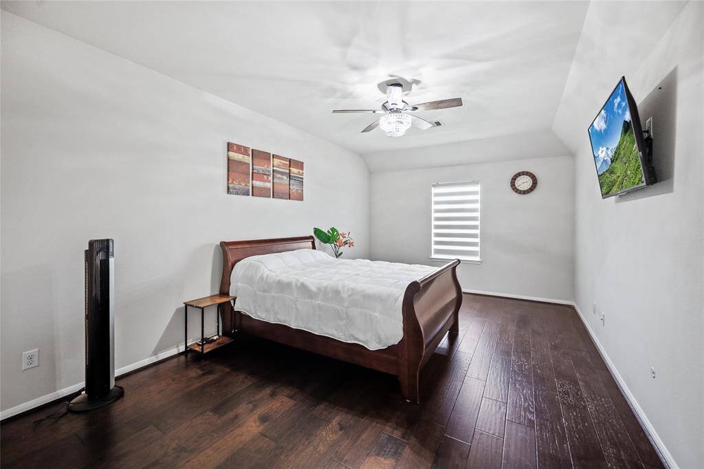Spacious and bright, Bedroom 3 features elegant wood flooring, a stylish ceiling fan, and ample natural light—perfect for relaxation or a cozy retreat.
