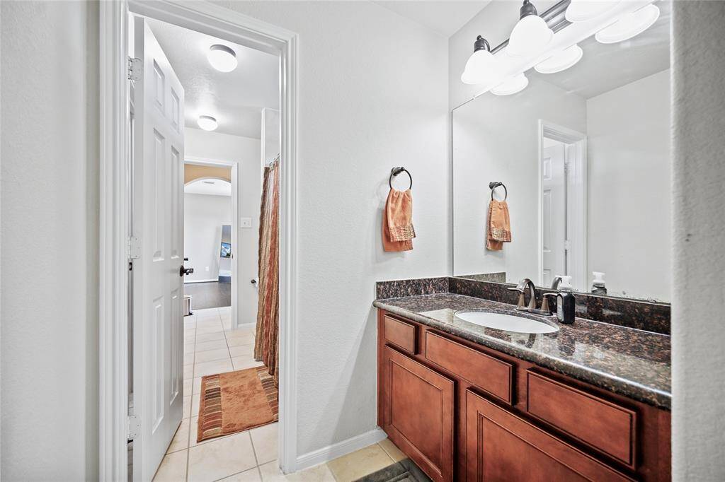 Modern and inviting third bathroom featuring sleek countertops, warm wooden cabinetry, and elegant fixtures. Ideal for guests or family use.
