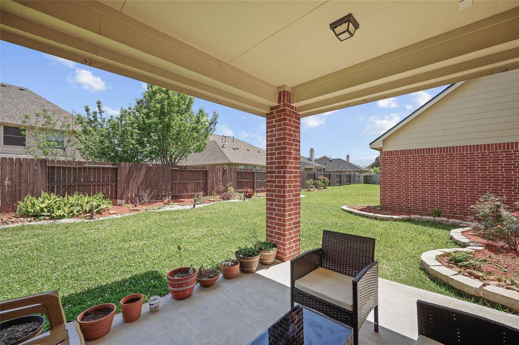 Outdoor covered patio overlooking a well-maintained backyard with a brick exterior.