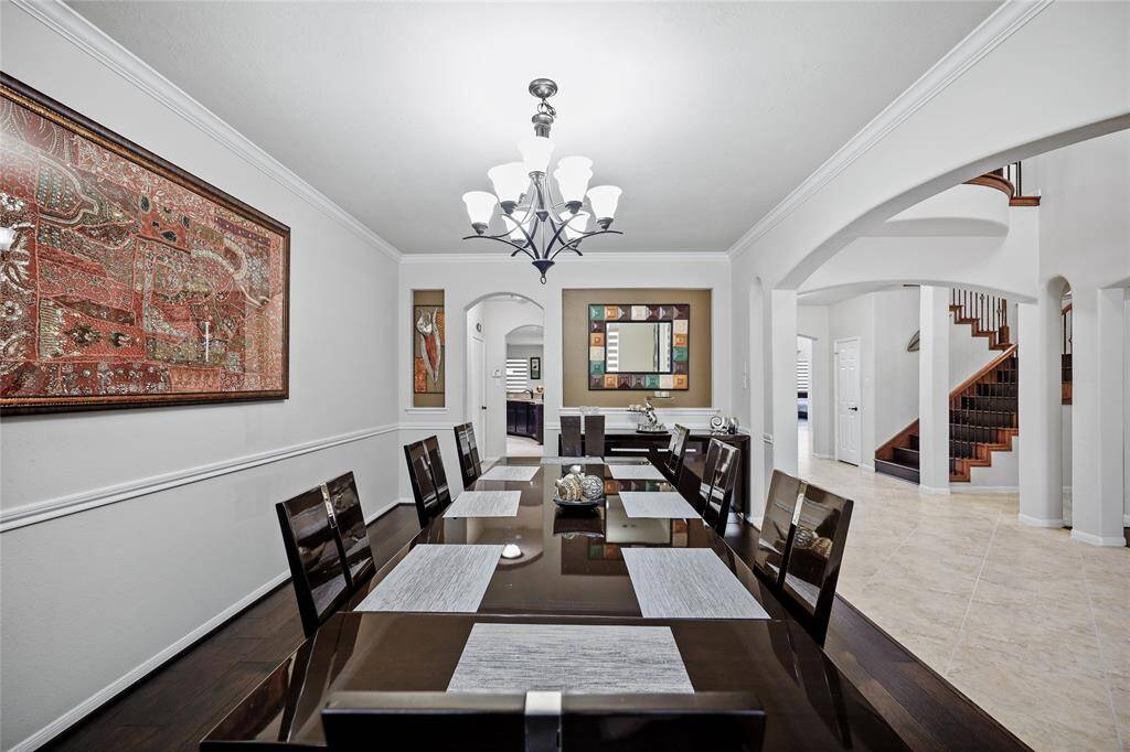 The formal dining space opens to a tiled hallway with a staircase, creating a seamless flow to the rest of the home.