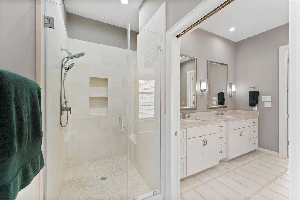 Indulge in the luxe shower featuring frameless glass, a built-in nook, and a bench.