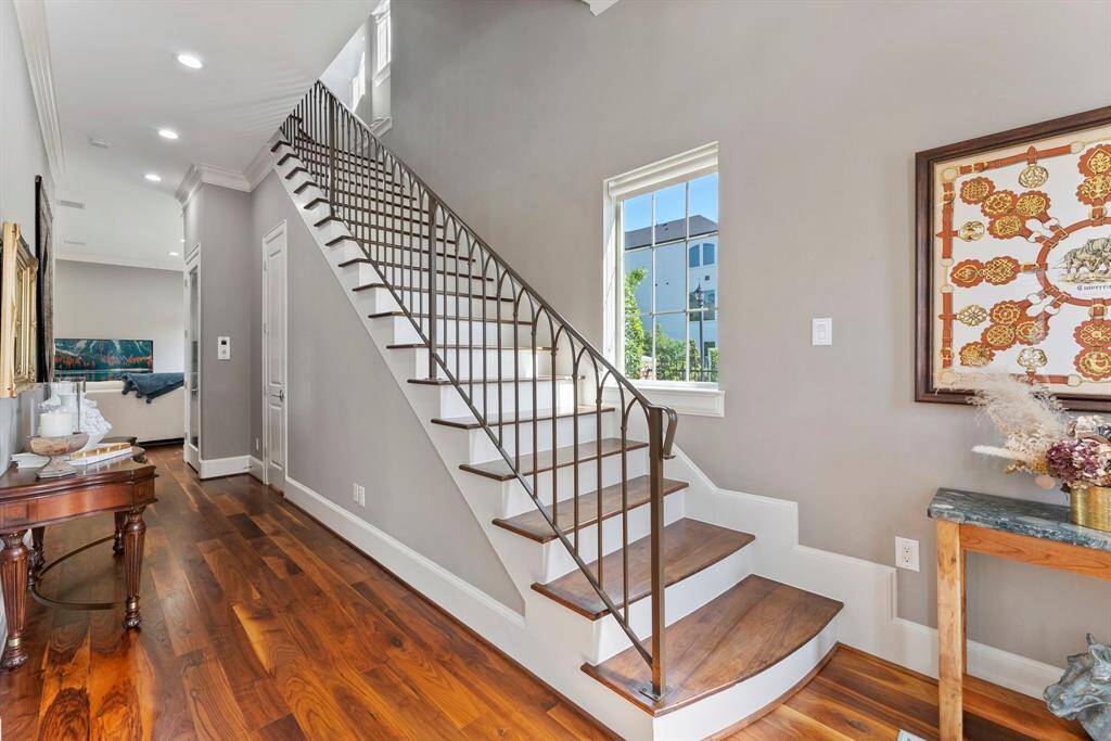 Stunning iron staircase with wood steps and natural light pouring in from windows on all three levels.