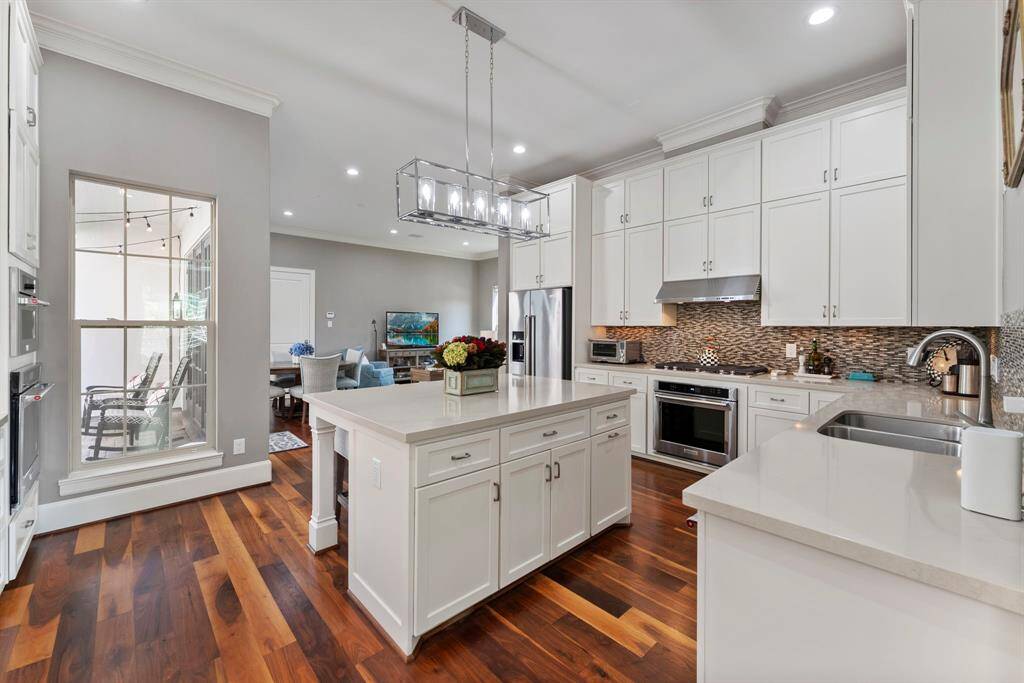 Beyond the formal living room, the kitchen boasts professional-grade appliances, custom cabinetry, sleek countertops, and a stylish tile backsplash.
