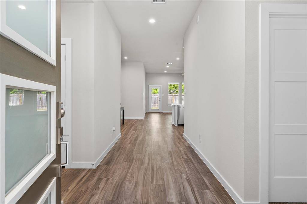 The entry hall flows seamlessly into a flexible living area framed by high ceilings and understated modern finishes. This space offers endless opportunities for customization, whether as a formal sitting area or an extension of the main living room.