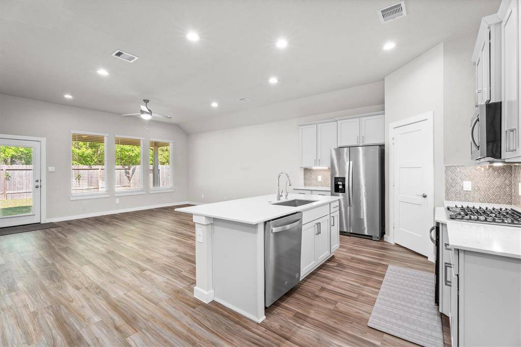 Open-concept kitchen with generous quartz countertops and a large island ideal for entertaining or casual dining. Recessed lighting, soft-close cabinets, and expansive counter space give this space a clean, high-end aesthetic. Luxury vinyl plank flooring adds warmth and continuity into the adjacent living spaces.