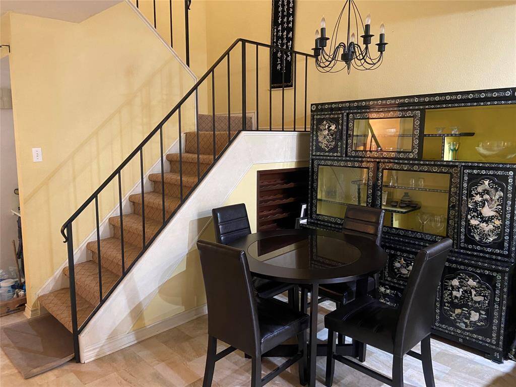 This inviting dining area features a stylish chandelier. The adjacent carpeted staircase adds charm and connects to the upper floor.