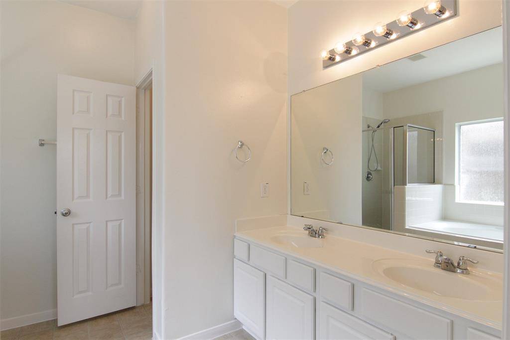 luxurious primary bath with 2 sinks at vanity, separate water closet, garden tub, separate glass shower