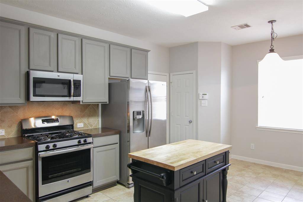 kitchen with 42" contemporary grey-painted cabinets, island with dark cabinets & butcher-board countertop