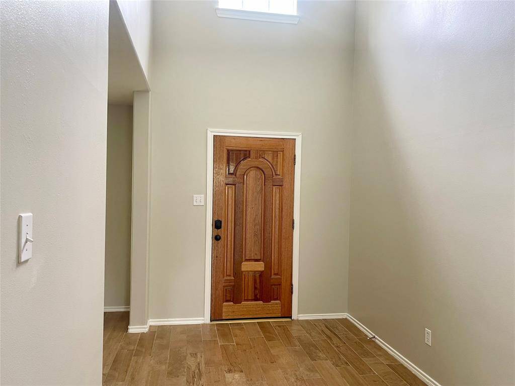 This photo shows a bright, carpeted upstairs hallway with a wooden handrail, leading to rooms with a ceiling fan and ample natural light from a large window.