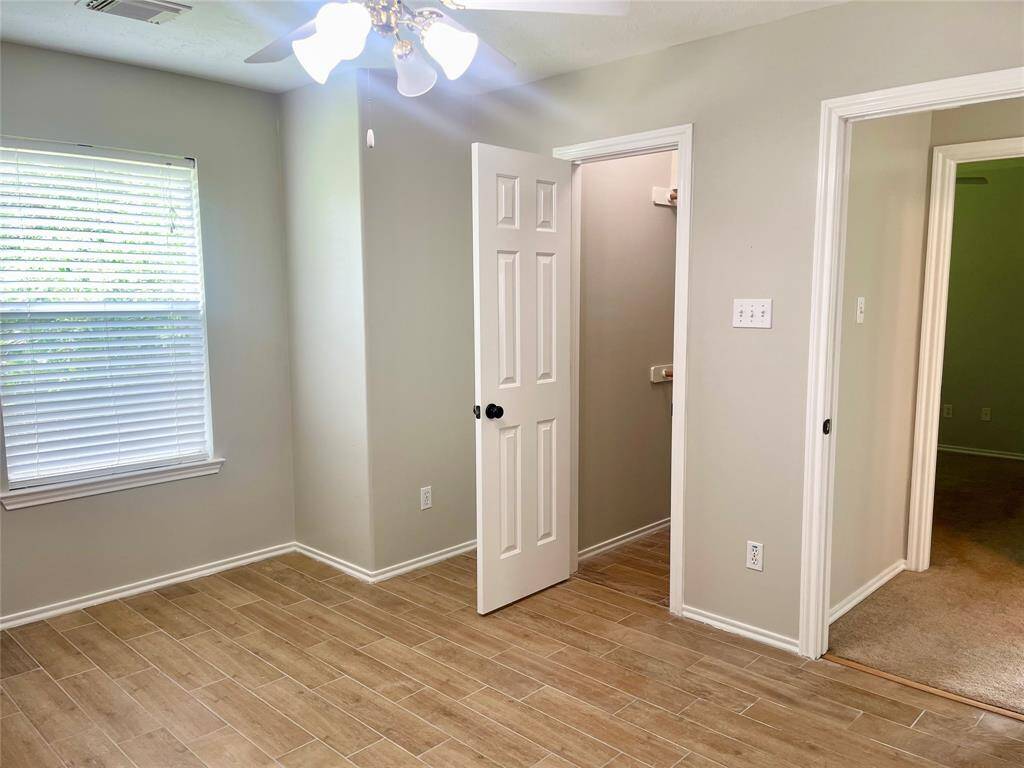 This photo shows a carpeted staircase with a wooden handrail leading down to a landing. The walls are painted in a neutral tone, providing a clean and simple look.