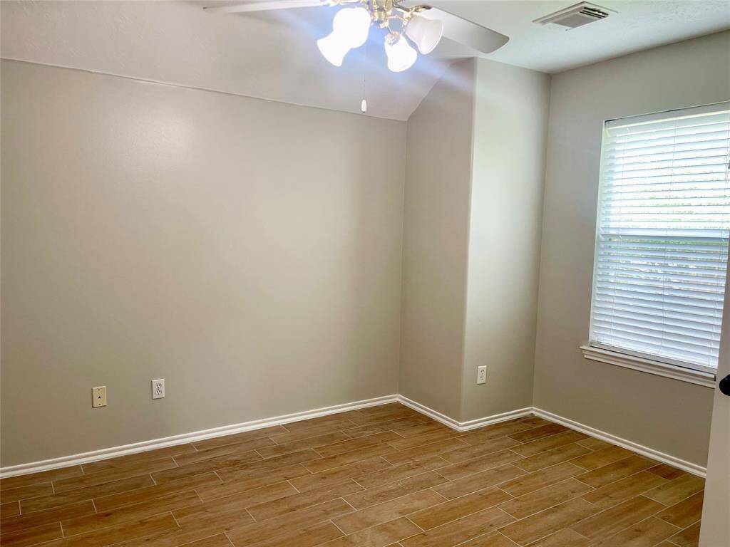 This photo shows a bright entryway with a wooden front door, elegant chandelier, and wood-look flooring. The space feels open and welcoming, with a neutral color palette.