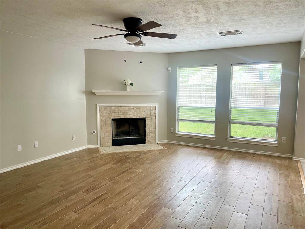 A spacious backyard with well-maintained grass, bordered by a wooden fence. The house features a mix of brick and siding, with multiple windows and a small patio area. Ideal for outdoor activities and relaxation. Ready for a pool