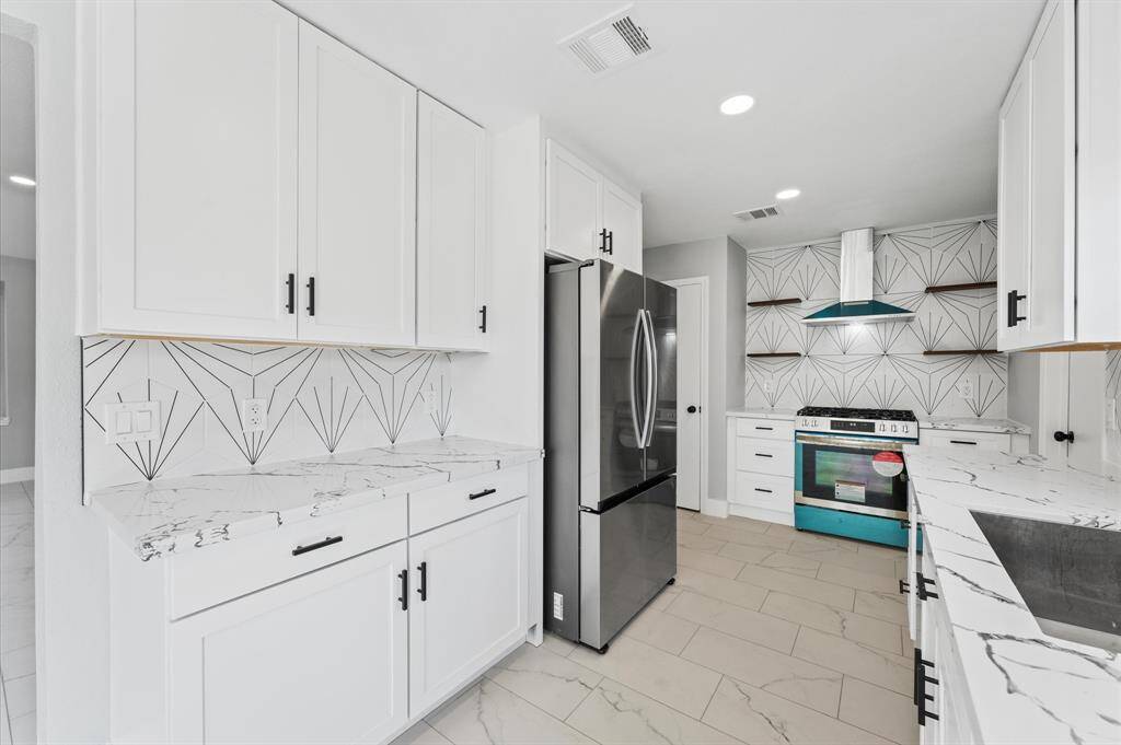 Sleek and modern: this remodeled kitchen boasts stainless steel appliances, bold black accents, and open shelving for a designer touch.