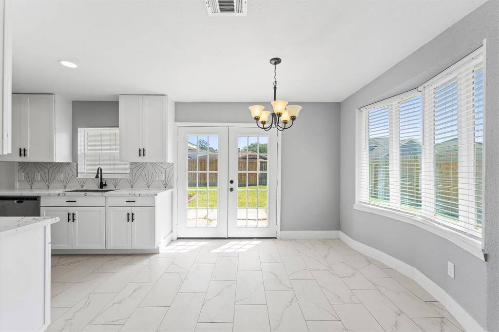 Bright and inviting dining room with large windows and French doors leading to a spacious backyard-perfect for indoor-outdoor entertaining.