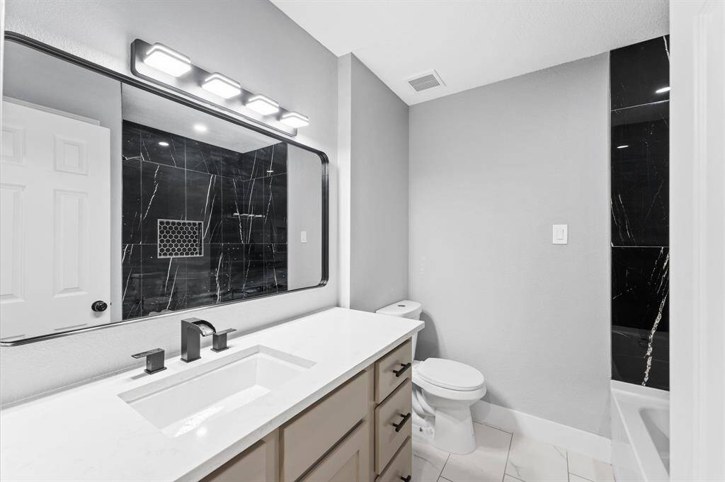 Spacious and stylish secondary bathroom offers refined design with black hardware and abundant storage.