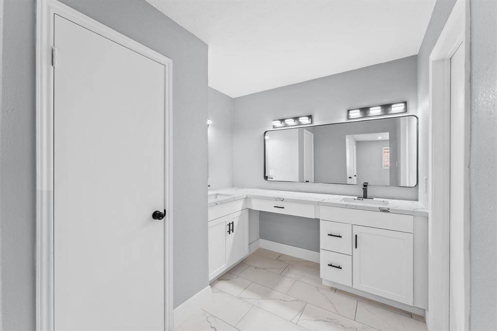 Luxurious primary ensuite bathroom featuring bold black tile, sleek double vanity, and ample linen storage for ultimate convenience