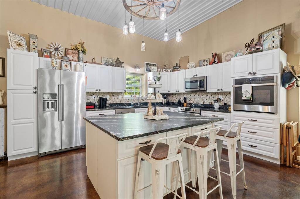 The gourmet kitchen is a true centerpiece, featuring crisp white cabinetry, granite countertops, stainless steel appliances, and a generous island with bar seating—perfect for entertaining guests or casual family meals. Refrigerator is negotiable.