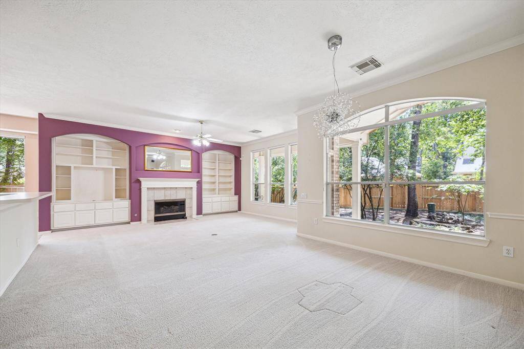 The expansive living area boasts impressive high ceilings and large windows that fill the room with natural light. A charming fireplace provides a cozy focal point, making it a desirable space for comfort and relaxation.