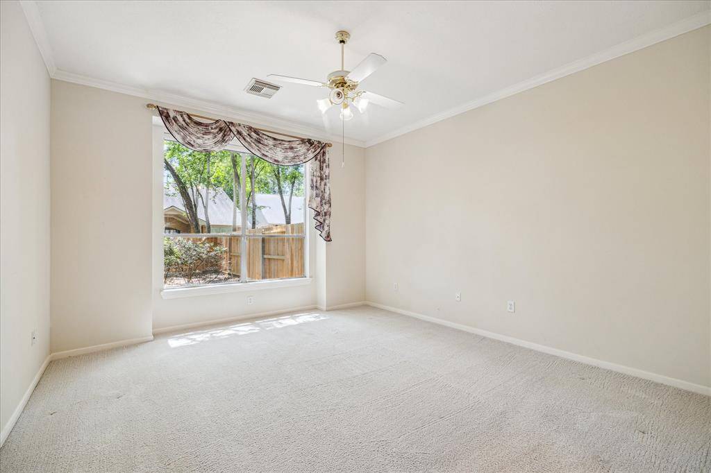 The serene primary bedroom is tucked at the rear of the home, offering a private retreat. Large windows fill the room with natural light, showcasing high ceilings and beautiful views of the lovely backyard space.