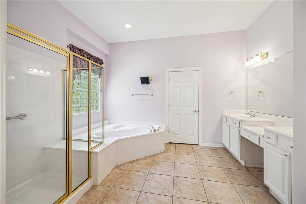 Generously sized, the primary bathroom features a separate shower and jetted tub. The dual sinks are complemented by a vanity area in between, providing both convenience and functionality. The space is further enhanced by a walk-in closet, adding to its overall appeal.