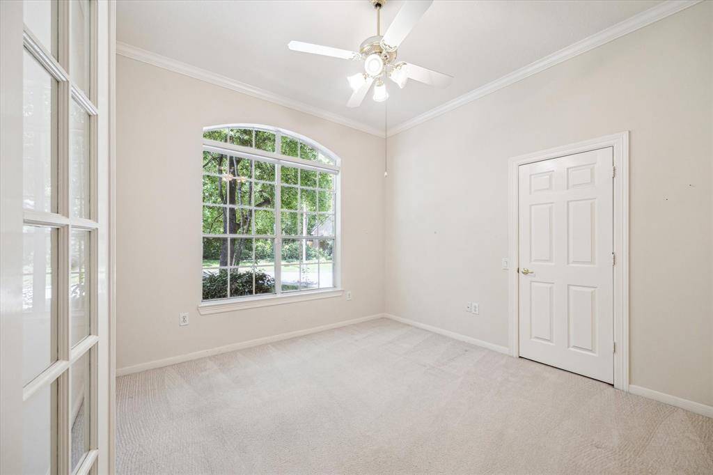 This well-appointed office is enclosed with French doors and offers a picturesque view of the front of the home, overlooking a tranquil, tree-lined landscape with no front neighbors in sight. An ideal space for productivity in a peaceful, private setting.