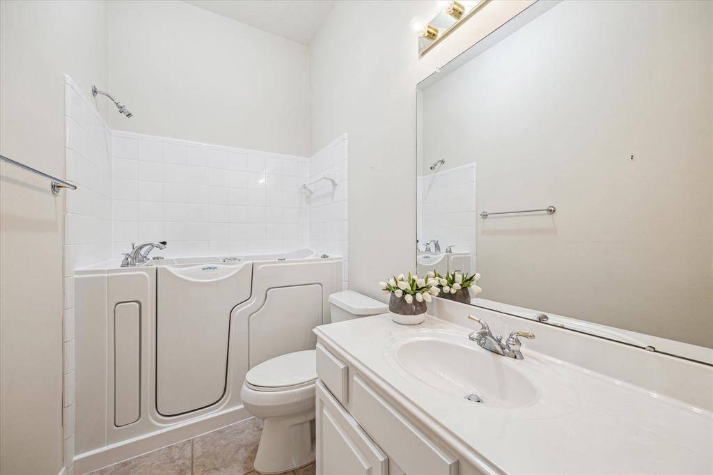 Located between the office space and secondary bedroom, this full bathroom is equipped with ample cabinet storage and drawers. It has been equipped with an easy-entry bathtub.