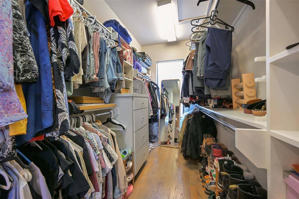 There is ample space for storage in this primary walk in closet with built in chest of drawers and shelving.